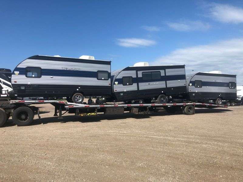 a travel trailer hauled on a flatbed trailer: camper shipping, camper towing, camper hauling, travel trailer transport, travel trailer hauling, travel trailer hauling